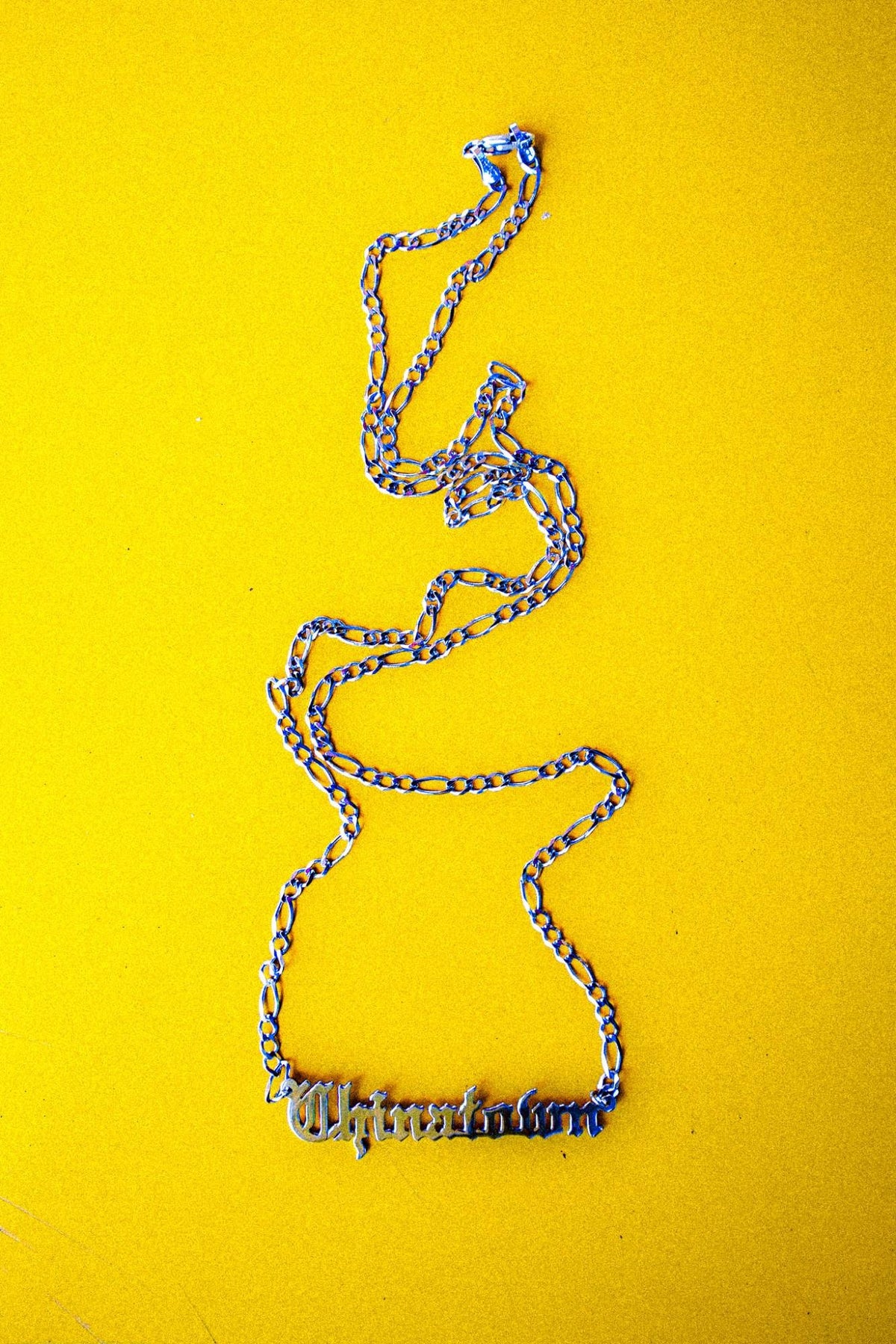 Chinatown Chain 14K white gold figaro chain with Old English nameplate, flat lay